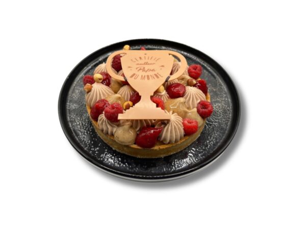 Tarte artisanale spéciale Fête des Pères, décorée de framboises fraîches, de crème pralinée et d’un trophée en chocolat avec l’inscription « Meilleur Papa du Monde »