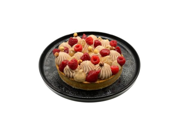 Cette tarte associe une pâte sucrée croustillante, un financier à la noisette, un confit de framboises acidulé, un crémeux praliné fondant et une chantilly au chocolat au lait origine Madagascar.